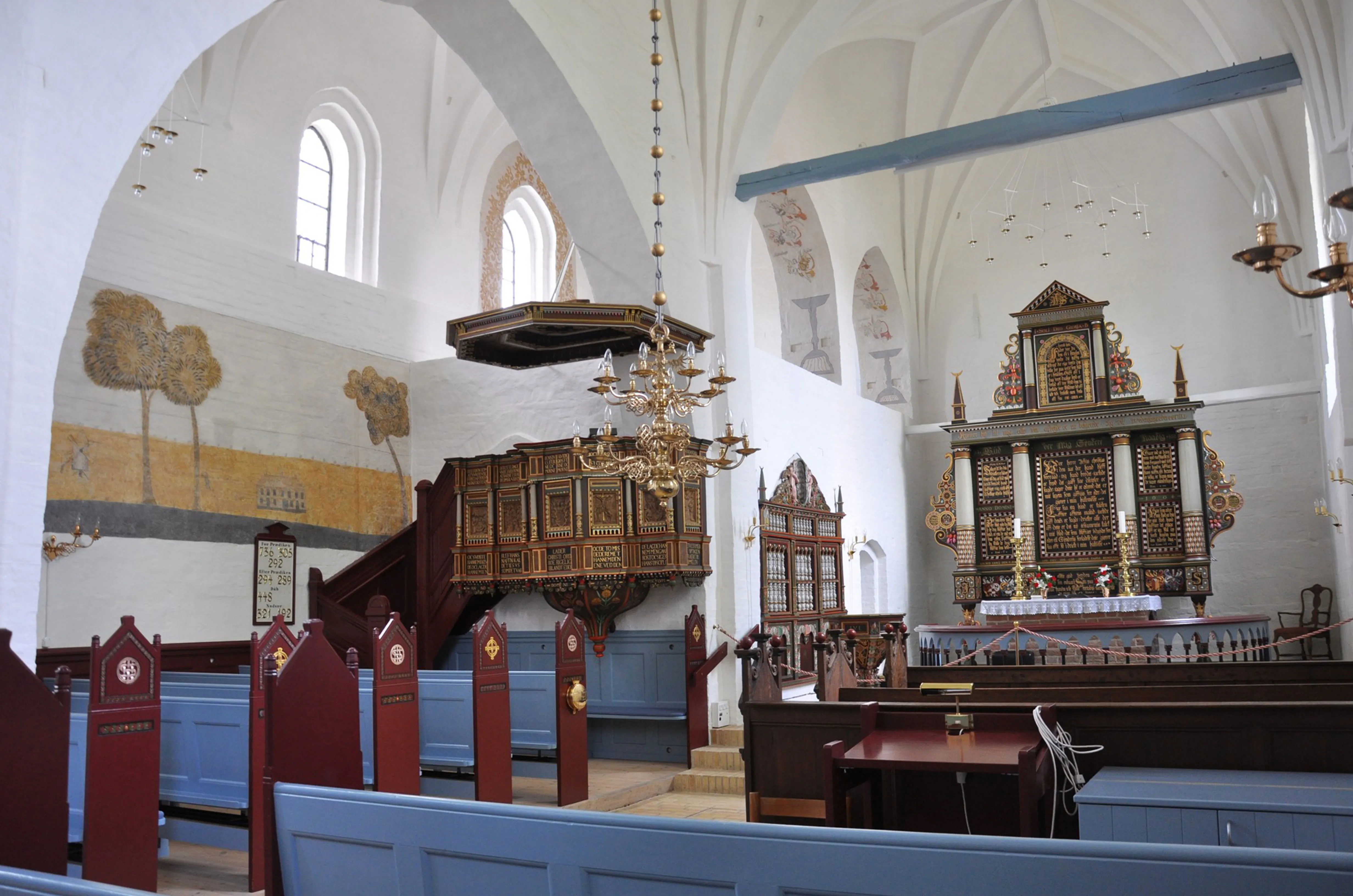 Interiør af en traditionel dansk kirke med en detaljeret træprædikestol og et alter.