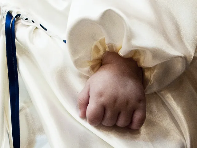 Babyhand in Taufkleid.