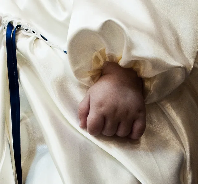 Babyhand in Taufkleid.