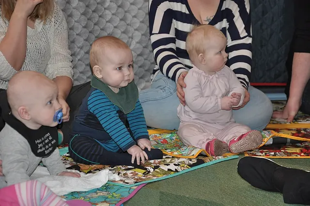 Drei Babys sitzen auf einer Decke.