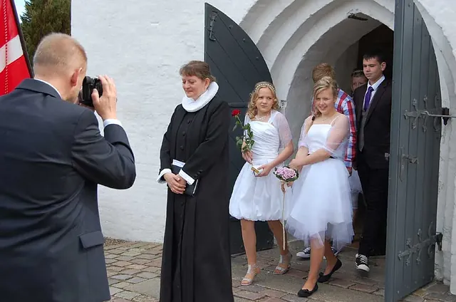 Fotograf macht Fotos von Menschen vor einem Kirchenportal.