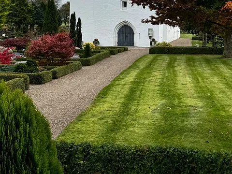 Kirkegård med hæk og grussti.